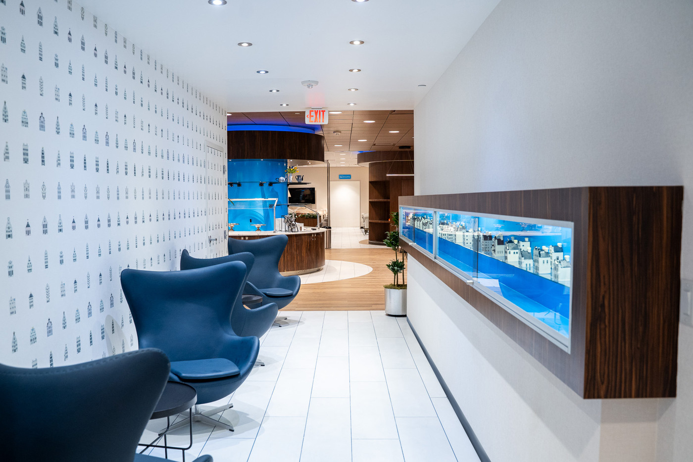 KLM Crown Lounge interior with signature Delft Blue house wallpaper, blue Egg chairs and illuminated display cabinet
